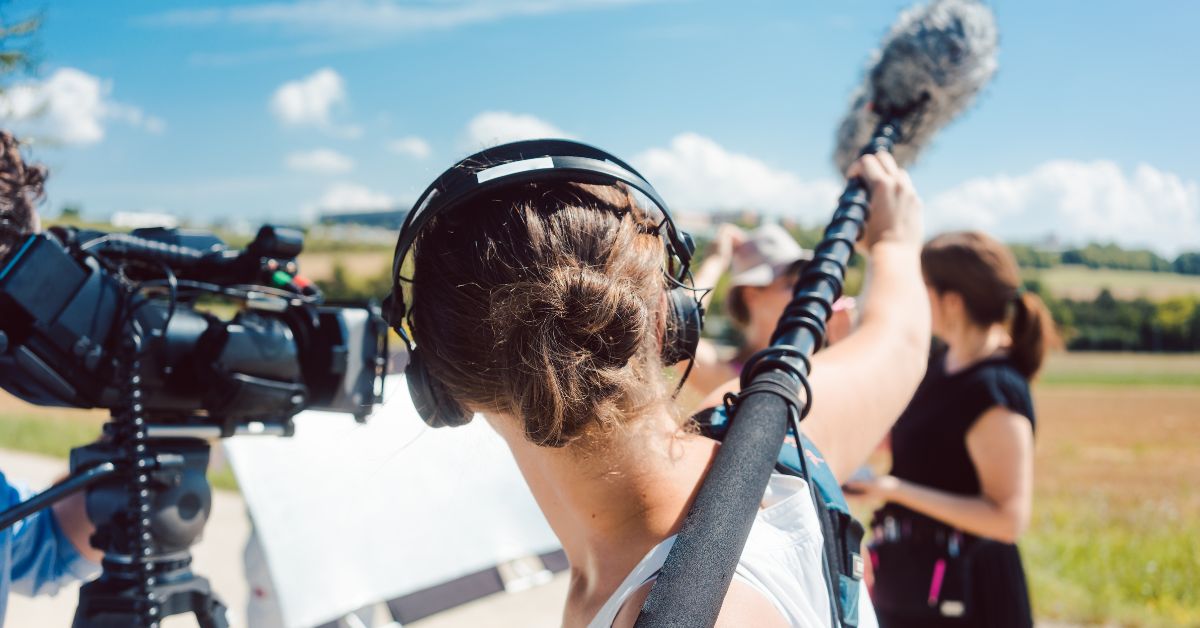 Film crew outside showing man holding boom microphone